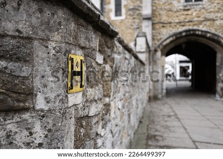 Shallow focus of a typical Hydrant yellow sign seen attached to a medieval wall. The distant shows an archway leading to market area.