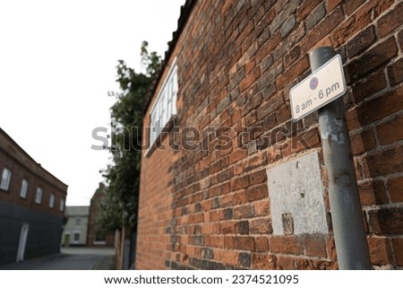 Shallow focus of a typical No Waiting street sign seen against a backdrop of an old brick wall in an English seaside town.