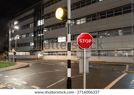 Shallow focus of a typical red Stop sign located by a pedestrian crossing on a medical and science campus in the UK. A science research building is in the background.
