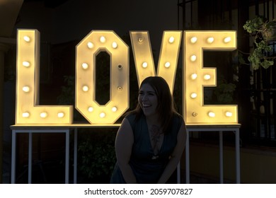 A Shallow Focus Of A Young Spanish Girl Standing In Front Of The Illuminated Word Love