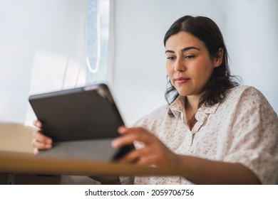 A Shallow Focus Of A Young Spanish Woman Using A Tablet Indoors