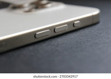 Shallow-depth macro of side controls on a contemporary smartphone, camera module blurred.