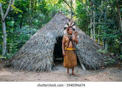 Shaman Of The Pataxó Tribe, Wearing Feather Headdress And Smoking A Pipe. Brazilian Indian Looking At The Right