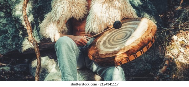 shamanic man playing on drum in the nature.