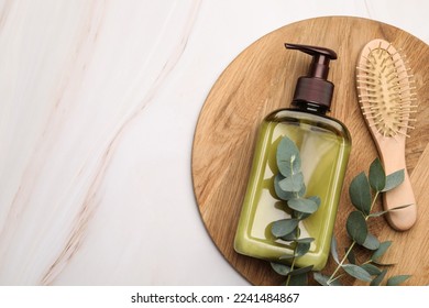 Shampoo bottle, hair brush and green leaves on white marble table, top view. Space for text - Shutterstock ID 2241484867