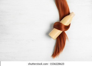 Shampoo bottle wrapped in lock of hair on white wooden background, flat lay with space for text. Natural cosmetic products - Shutterstock ID 1536228623