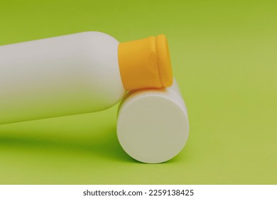 Shampoo for hair in a white package with a yellow cap on a green background - Shutterstock ID 2259138425