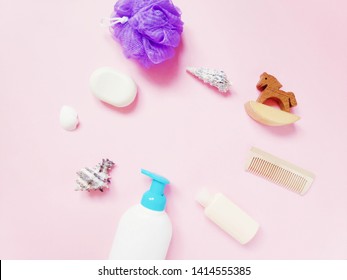 Shampoo, soap, purple puff sponge and toy wooden horse on a pink background. Flat lay beauty photo