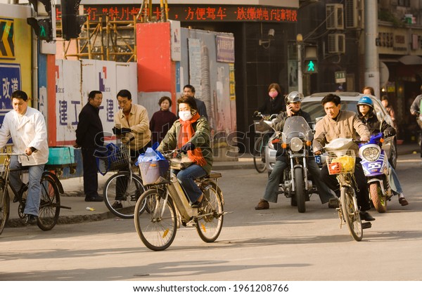 Shanghai, China, Asia - Woman riding\
a bicycle with face mask in the chaotic traffic of\
Shanghai.
