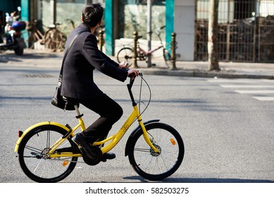 Shanghai, China - February 18, 2017: Young man riding a bicycle of the bike sharing company Ofo. Ofo is one of the dominating bike sharing providers in Shanghai