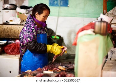 Shanghai, China - February 18, 2017: Female Fish Vendor Eviscerating Fish At Chinese Wet Market