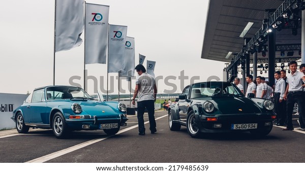 Shanghai,\
China- July 8,2022: a black Porsche 930 Turbo 3.3 and a blue\
Porsche Targa Coupes are parked in\
courtyard