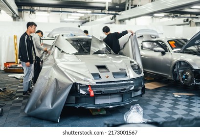 Shanghai, China- June 26,2022: A Group Of Mechanics Are Working On Two Silver Porsche 992 GT3 Cup Sportcars In Garage