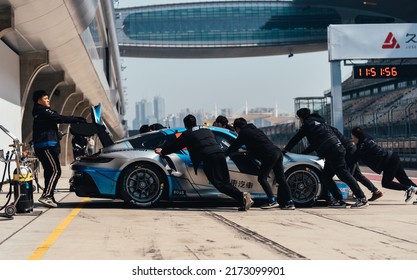 Shanghai, China- June 26,2022: A Group Of Mechanics Are Pushing A Porsche 992 GT3 Cup Sportcar In Courtyard