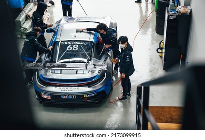 Shanghai, China- June 26,2022: A Group Of Mechanics Are Working On A Porsche 992 GT3 Cup Sportcar In Garage