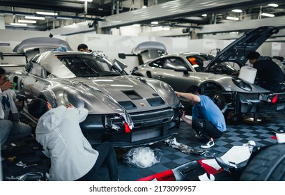 Shanghai, China- June 26,2022: A Group Of Mechanics Are Working On Two Silver Porsche 992 GT3 Cup Sportcars In Garage