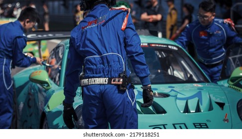 Shanghai, China- June 26,2022: A Group Of Mechanics In Blue Uniforms Are Working On A Green Porsche 911 GT3 Sportcar In Courtyard