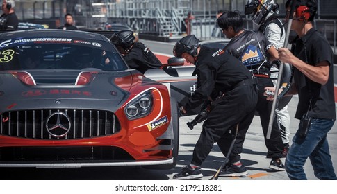 Shanghai, China- June 26,2022: A Group Of Mechanics In Black Uniforms Are Working On A Black Mercedes-AMG GT3 Sportcar In Courtyard