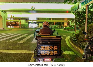 SHANGHAI, CHINA - Oct 19, 2020: A Delivery Man In A Helmet Riding A Motor Scooter On The Street At Night