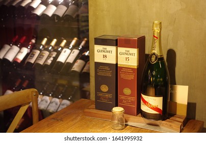 Shanghai, China - Oct 22, 2015: G. H. Mumm champagne and The Glenlivet single malt scotch whisky packages displayed on wooden table with bottles of wine in rack at vintage bar