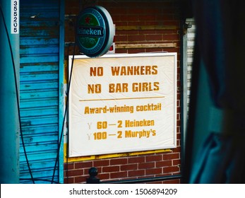 Shanghai, China - October 12 2013: Amusing Sign Outside Shanghai Bar, Advertising Cocktails, Heineken And Murphy's But Banning Wankers And Bar Girls. Brick Wall In Background.