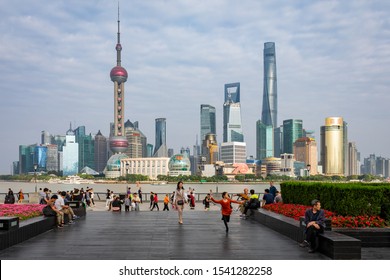 Shanghai, China - Octobre 12, 2019; City View From The Bund Over River Huangpu To City Centre Skyline With Oriental Pearl Tower And Jin Mao Tower And Shanghai Tower People Enjoy Walking The Boulevard