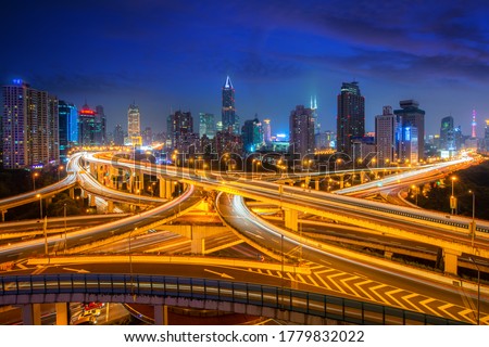 Shanghai elevated road junction and interchange overpass with office buliding skyscrapers downtown district at night in Shanghai, China. Asian tourism, modern city life, or business finance