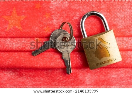 Shanghai lockdown: a lock with a Shanghai map and the word lockdown engraved on a pair of key over a surgical mask with chinese flag