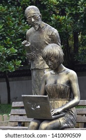 Shanghai, October 11, 2016:  Statues on a  street of Jiading  district.  A traditionally dressed old man is watching a modern sexy young girl using a laptop. 