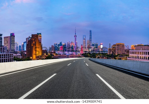 Shanghai skyline panoramic view with asphalt\
highway at night,China