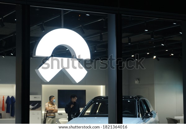 Shanghai,China-Sep.2020:close up NIO brand logo in\
store at night. NIO is a Chinese electric car brand. \
 Customers\
inside buying electric\
car