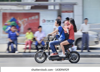 SHANGHAI-JUNE 3. Couple With Their Child On An Electric Bike. China's Government Family Planning Policy Officially Restricts Married, Urban Couples To Having Only One Child. Shanghai, June 3, 2013.