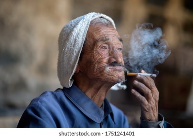 Shanxi, China. May 19, 2012. An Old Chinese Village Male Worker Smoking Cigarette. Senior Face Portrait.