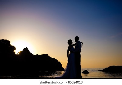 Shape of a bride and groom on the beach at sunrise time