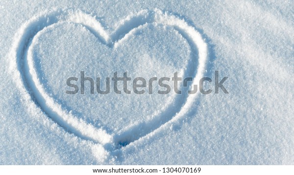 Shape of a heart\
in the light blue bright snow. Close up leftside view. Valentine\'s\
day pattern. Symbol of\
love