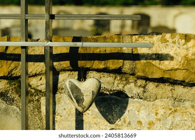 A shape of heart made of stone hanging on a metal stands in the cemetery.