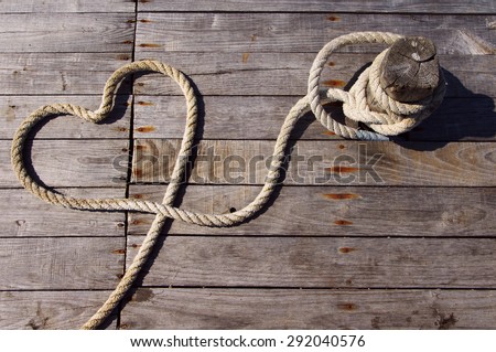 Shape of heart from a rough rope on a textural wooden pier . Heart from a sea rope. Valentine's Day card