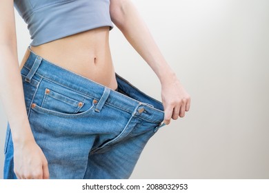 Shape slender, thin waist, attractive slim asian young woman, hand show shape her weight loss, wearing in big, large or oversize jeans, excess lose by diet and exercise. People body fit healthy. - Shutterstock ID 2088032953