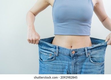 Shape slender, thin waist, attractive slim asian young woman, hand show shape her weight loss, wearing in big, large or oversize jeans, excess lose by diet and exercise. People body fit healthy.