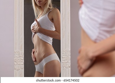 Shape Woman checking her body in front of mirror. Slim female, waist,torso, abdomen close up. Healthy nutrition and weight losing concept - Shutterstock ID 654174502