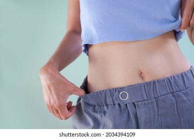Shapely waist woman close up on green cement wall background. authentic body slim fit and skin tan asian thailand female. diet loss weight for good health lifestyle concept. - Shutterstock ID 2034394109