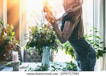 Woman making wild flowers at home in vase