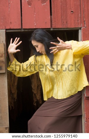 Shapes of a dancer in Earth tones complement a doorway in the side of a red barn on a farm in Ellington, Connecticut.