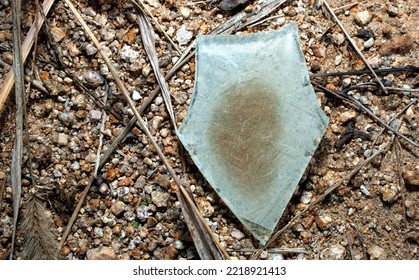 A Shard Of Glass Weathered By Time Reflects The Light Of The Day While Laying In A Pile Of Pine Needles In A Roadside Stone Sculpture Park. It Looks Like An Old Arrowhead.