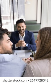 Shared decision making. Smiling bank manager finance consultant legal adviser wait as young spouses clients discuss house buying options share opinions on loan proposal make choice of investment offer