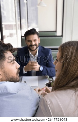 Shared decision making. Smiling bank manager finance consultant legal adviser wait as young spouses clients discuss house buying options share opinions on loan proposal make choice of investment offer
