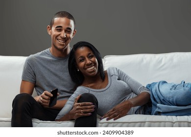 Shared laughter between two young lovers, cozily reclining on a sofa, capturing a joyful moment
