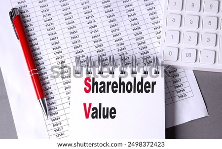 SHAREHOLDER VALUE text on a notebook with chart , pen and calculator. 