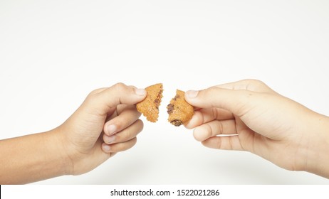 Sharing concept, a hand of brothers holding half piece of cookies - Powered by Shutterstock