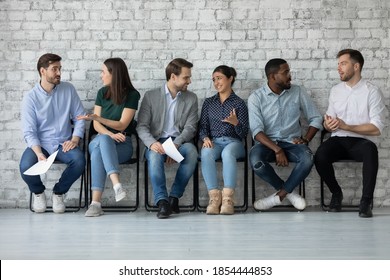 Sharing impressions. Couples of diverse multinational businesspeople job seekers students sitting on chairs in office university hallway talking exchanging opinions discussing interview exam results